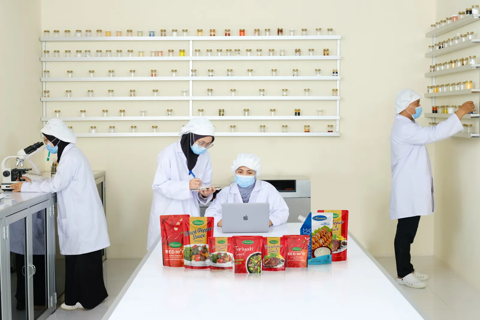 Tim QC Mazzoni memeriksa sampel di laboratorium, dengan lini pengemasan saus di baliknya